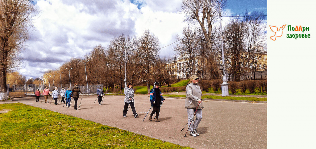группа пенсионеров занимается скандинавской ходьбой на набережной